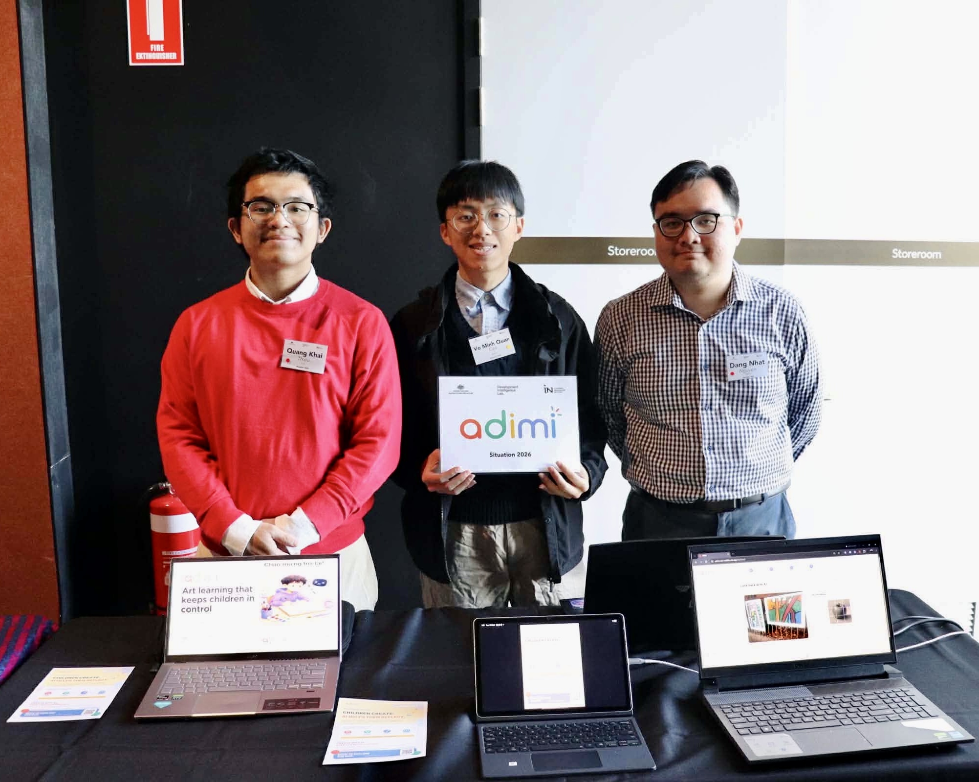 Adimi team members at their exhibition booth holding the adimi logo